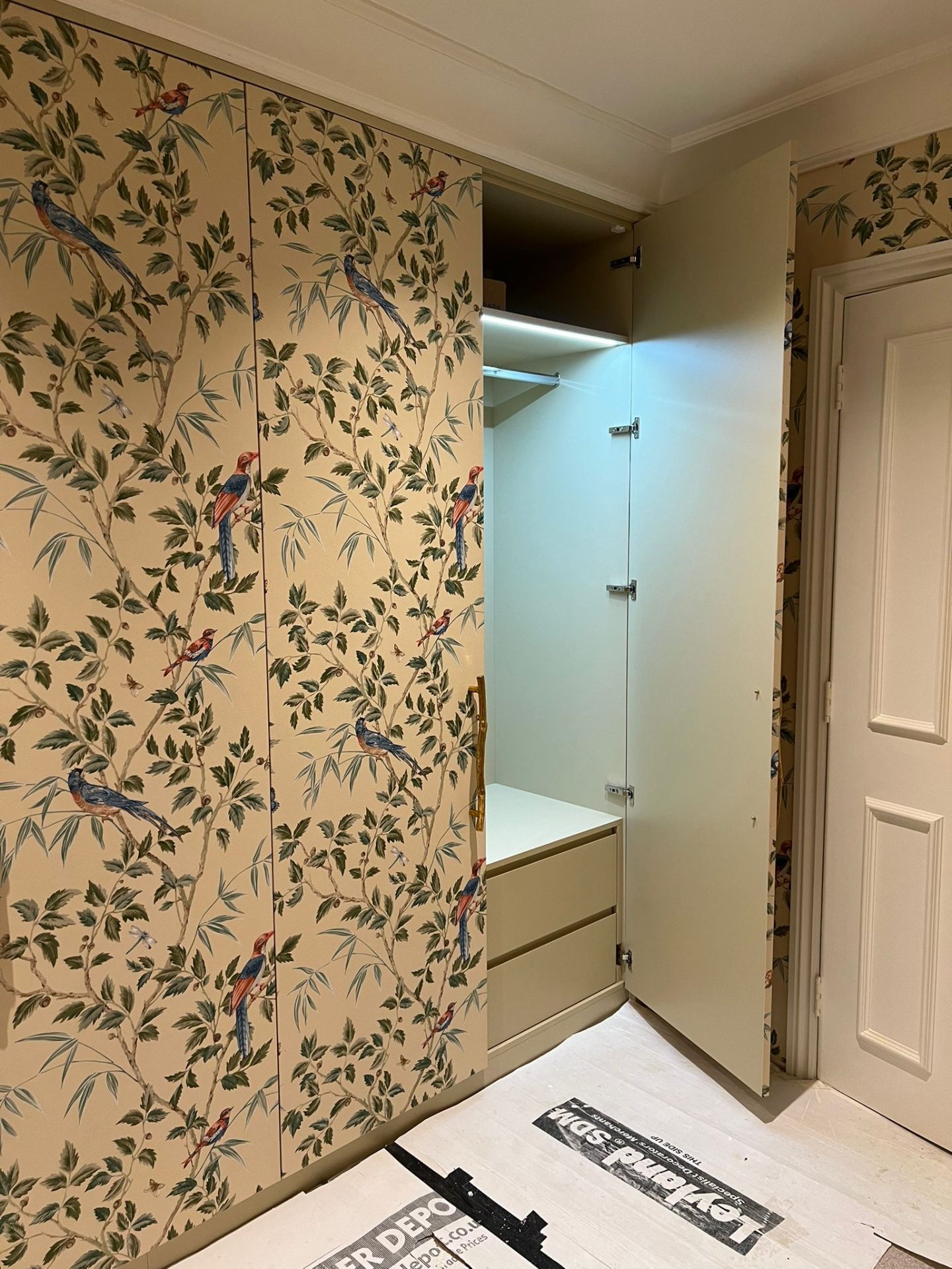 Bespoke fitted wardrobe open to reveal LED-lit interior, hanging rail and drawer stack, design and build project by Ash Villa