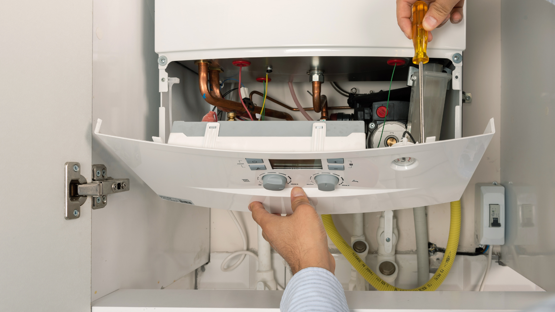Engineer's hands working on a newly installed white wall-mounted Vaillant condensing boiler with the front cover removed — Ash Villa Gas Safe boiler installation in West London