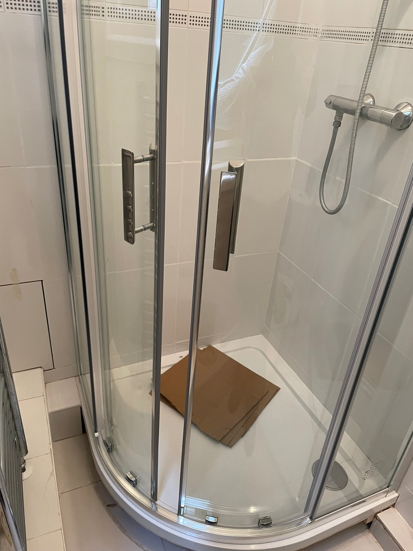 Quadrant shower enclosure with sliding chrome doors and thermostatic shower valve, installed in a family bathroom