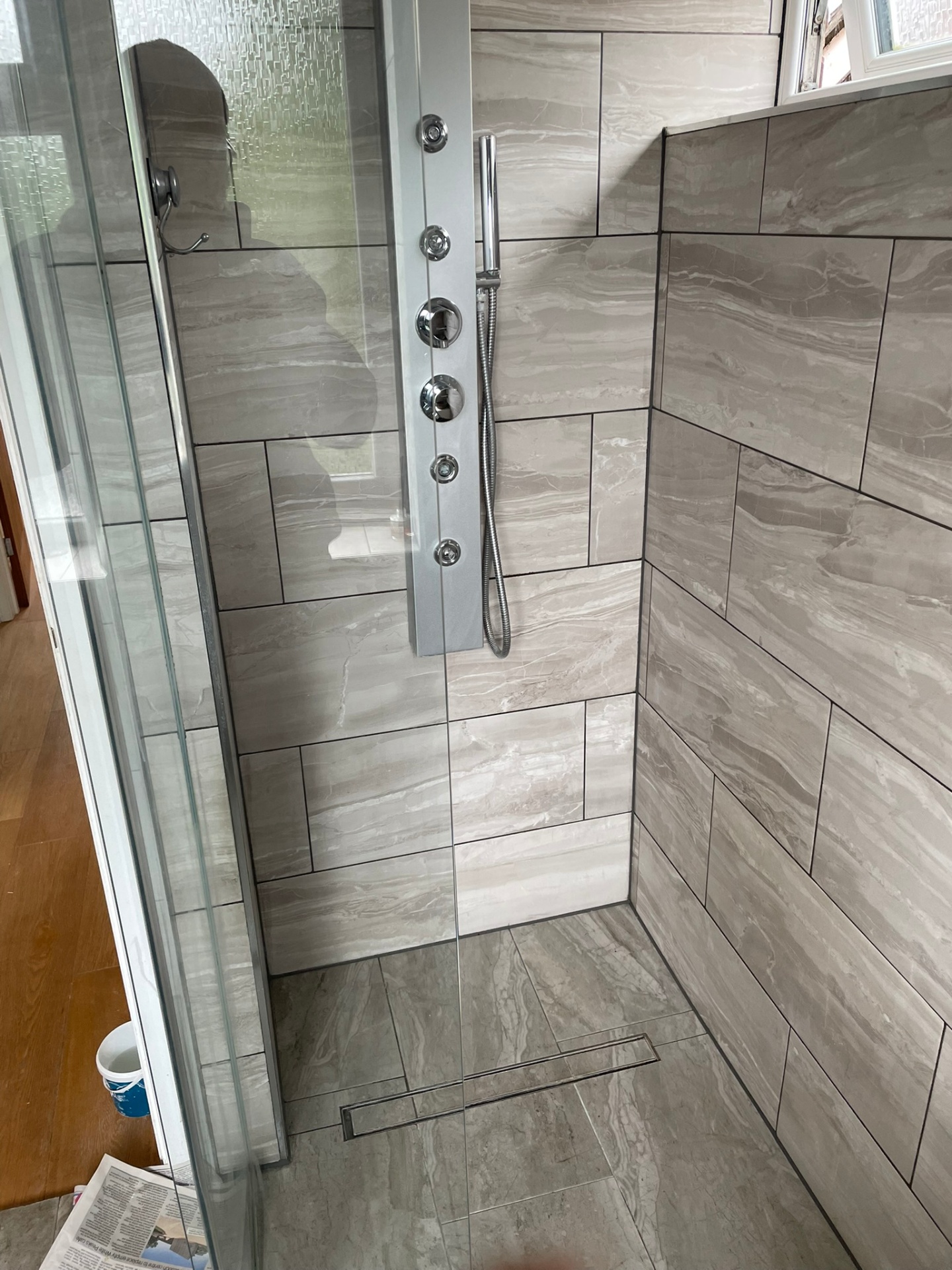 Wet room shower area with grey marble tiles, vertical shower panel and linear floor drain — Ash Villa wet room installation