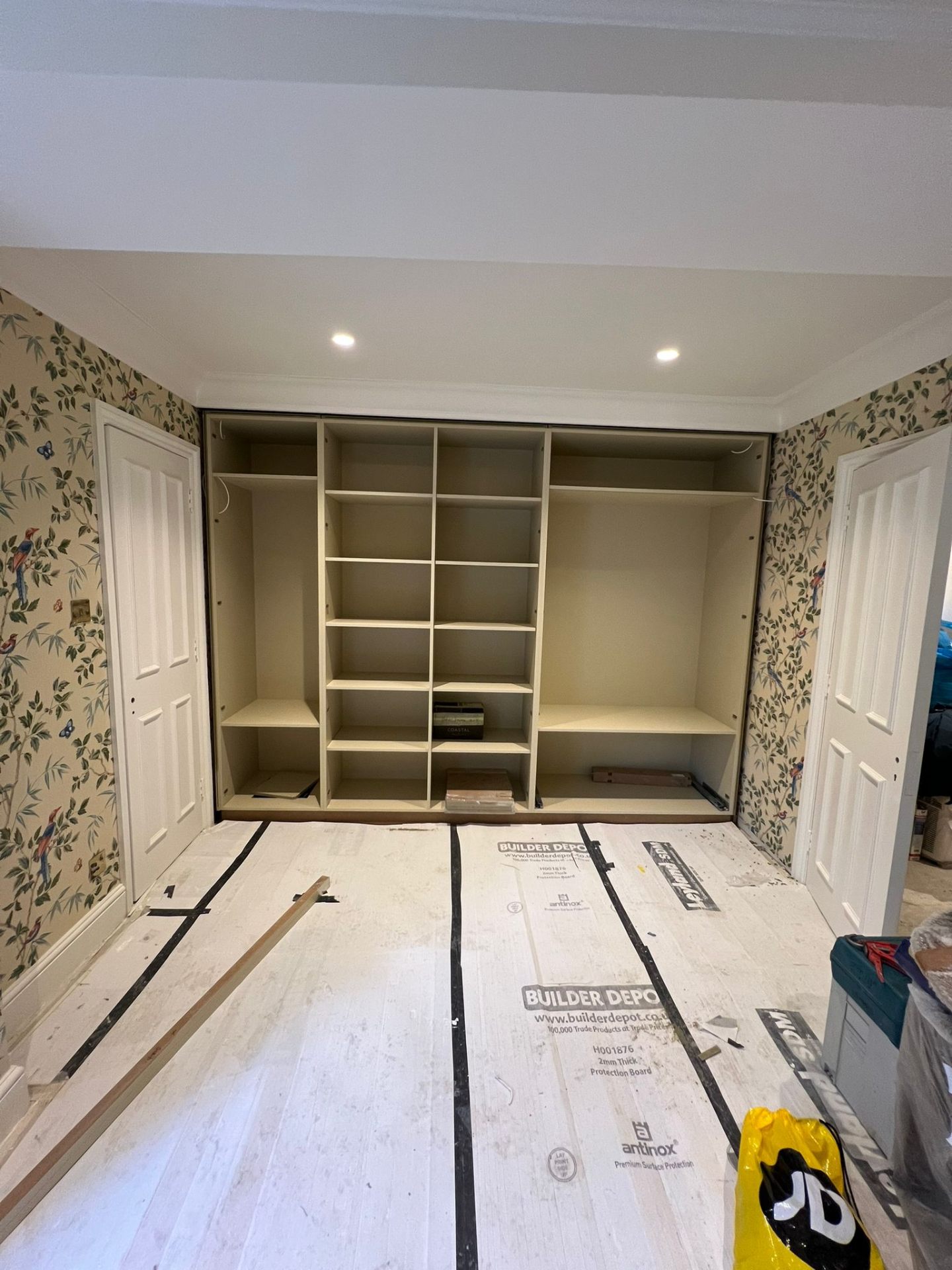 Fitted wardrobe carcass installation in Acton — internal shelving, hanging rails and drawer runners before doors are fitted