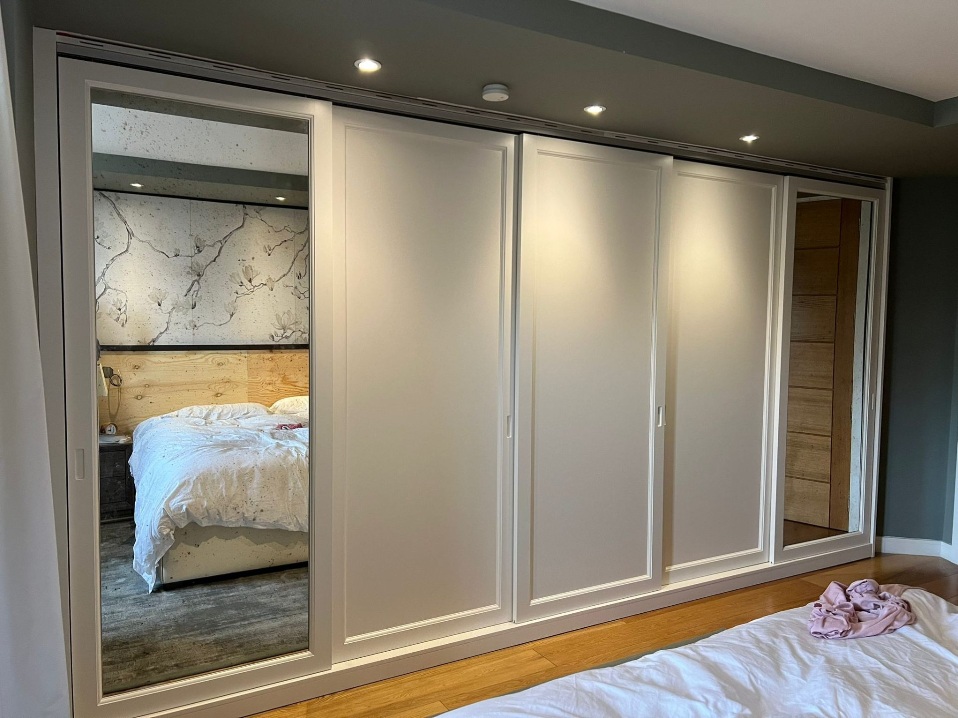 Fitted sliding-door wardrobe in painted finish with mirrored end panels — bespoke joinery by Ash Villa